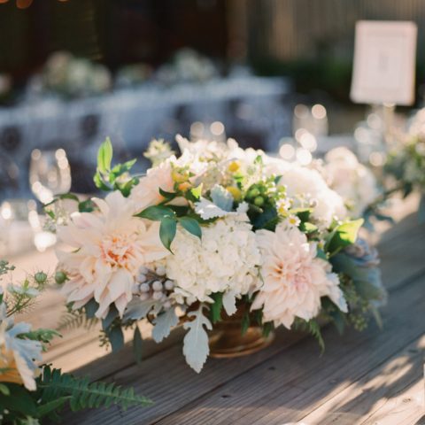 Wooden table with white floral centerpieces and white candle