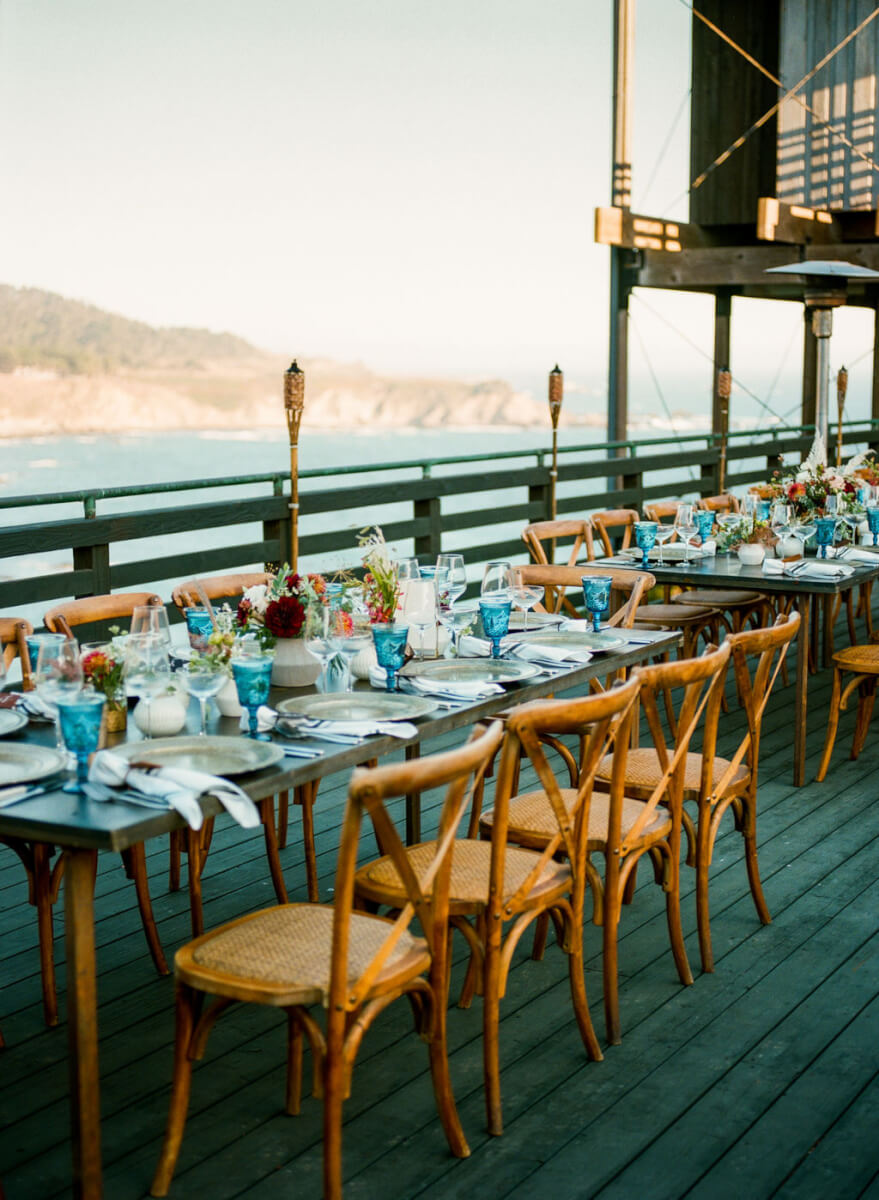 Wedding reception table fully set with floral arrangements on outdoor deck overlooking Sonoma County ocean