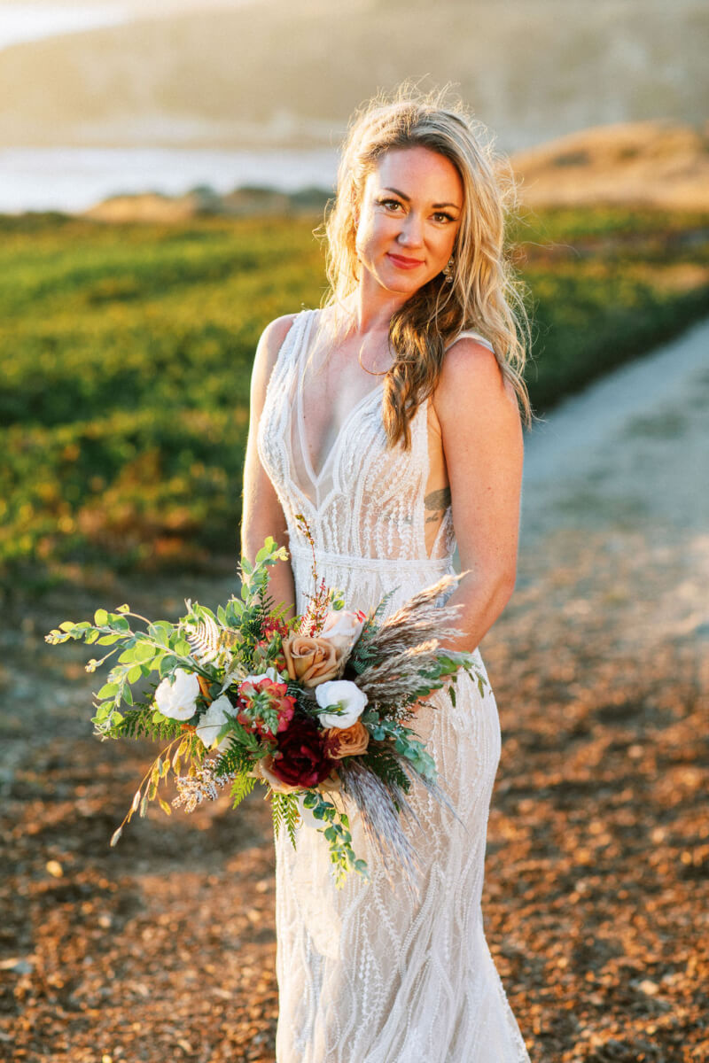 Bride holding floral wedding bouquet outside with Sonoma County ocean in background