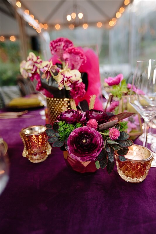 Vibrant pink birthday event floral arrangements set up on table next to candles