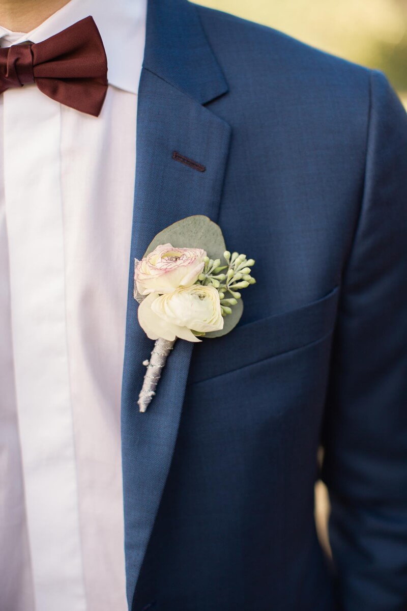 White floral wedding corsage pinned on blue blazer