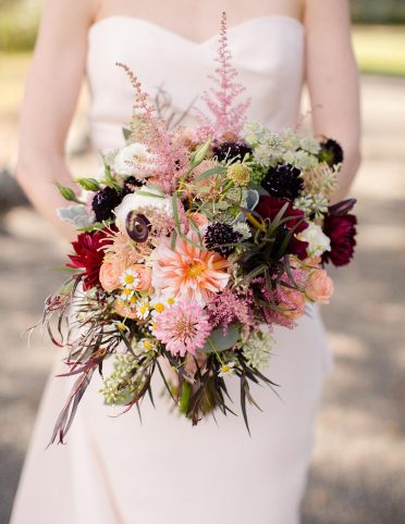 Bride holding bridal bouqet made with wild flowers, dahlias, zinnias, and scabosia