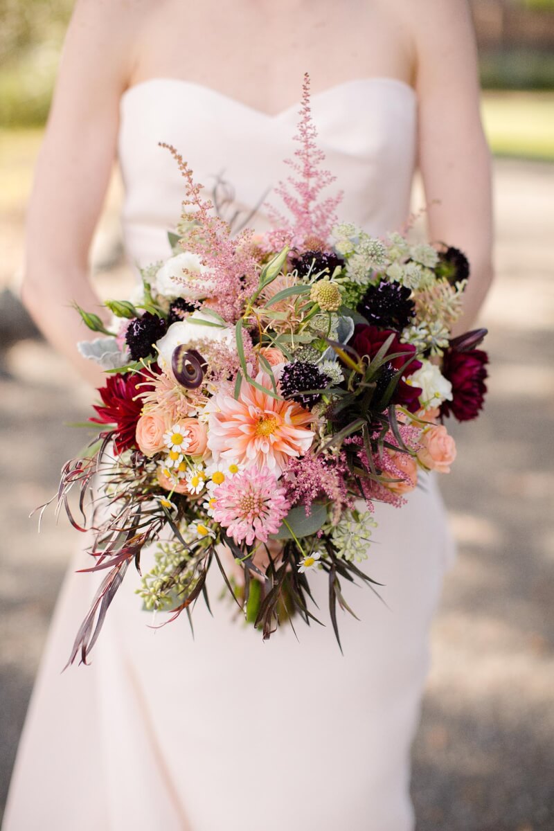 Bride holding bridal bouqet made with wild flowers, dahlias, zinnias, and scabosia