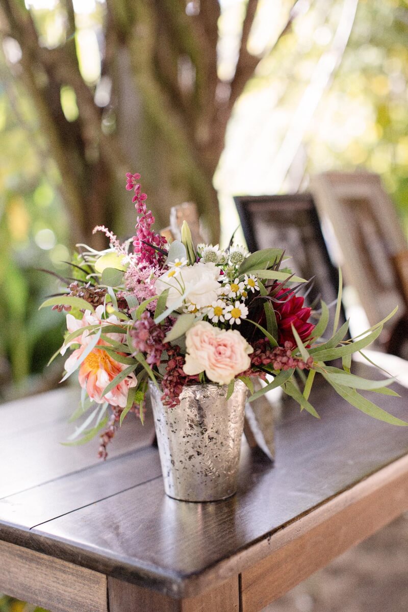 Rustic wedding floral arrangement on outdoor wooden table