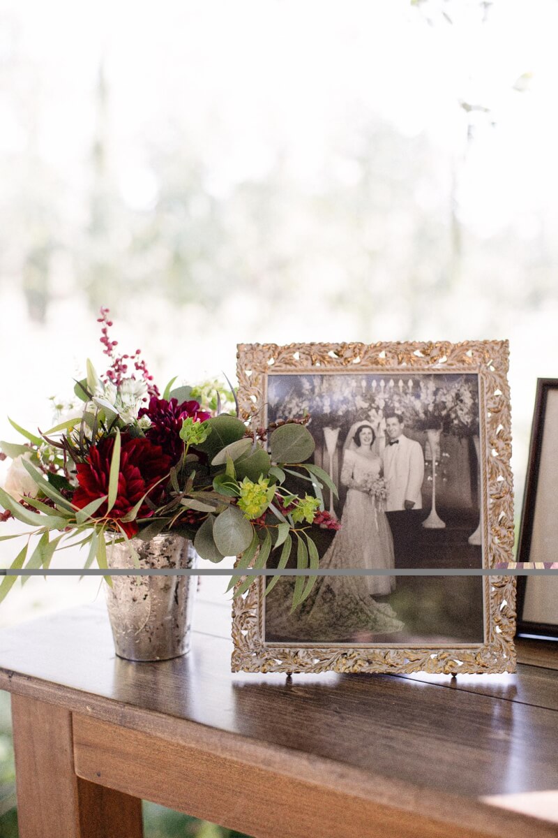 Decorative rustic wedding floral arrangement on wooden table next to vintage wedding photo