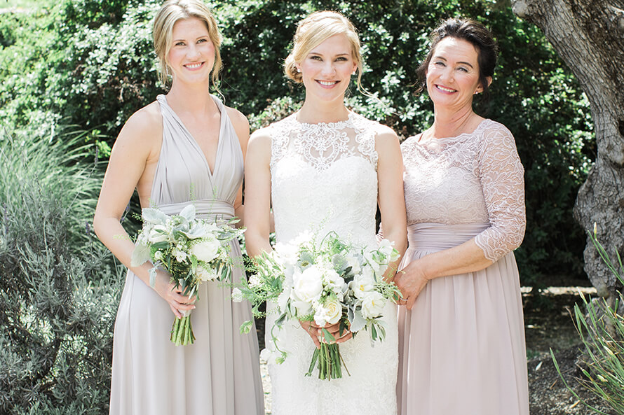 Bride with bridesmaid and mother holding wedding bouqets outdoors at Promontory Winery wedding in Napa