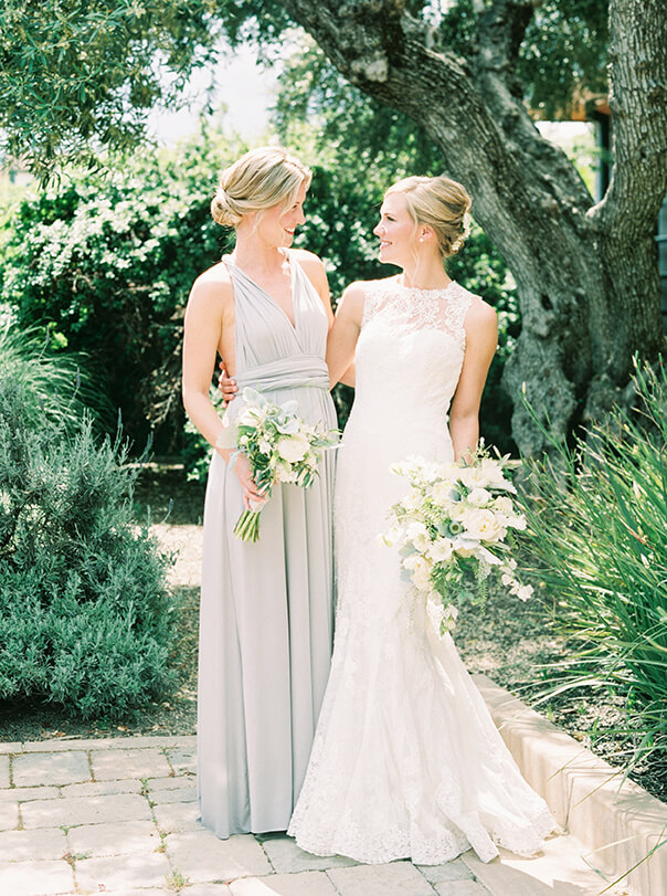 Bride and bridesmaid holding white flower wedding bouquets outdoors at Promontory Winery wedding in Napa