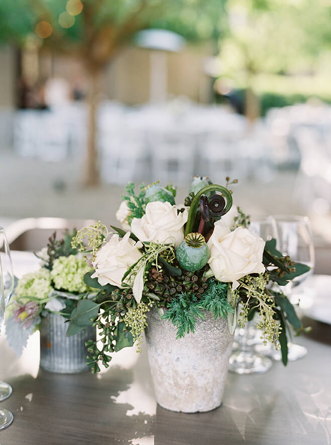 Rustic wedding flower centerpiece set utop wooden table outdoors at Promontory Winery wedding in Napa