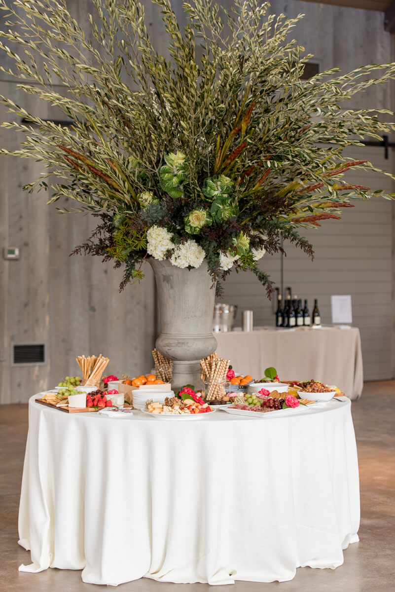 Large floral arrangement centerpiece on table with white tablecloth and hors d'oeuvres