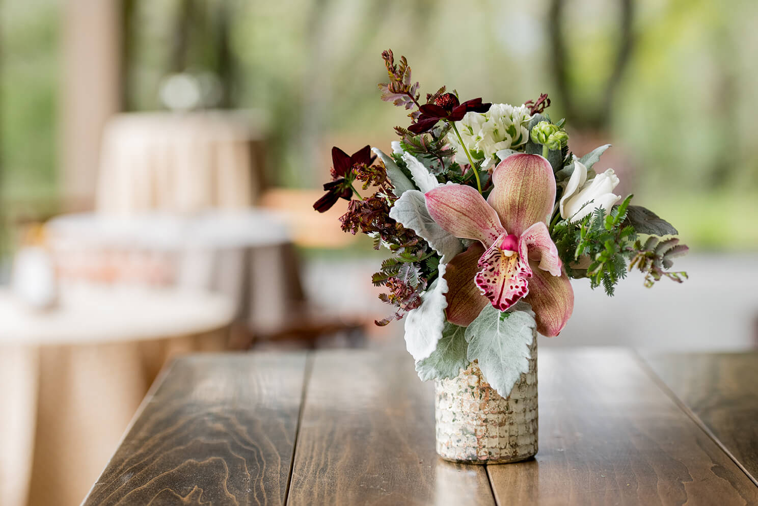Rustic floral arrangement on wooden table in outdoor winery venue