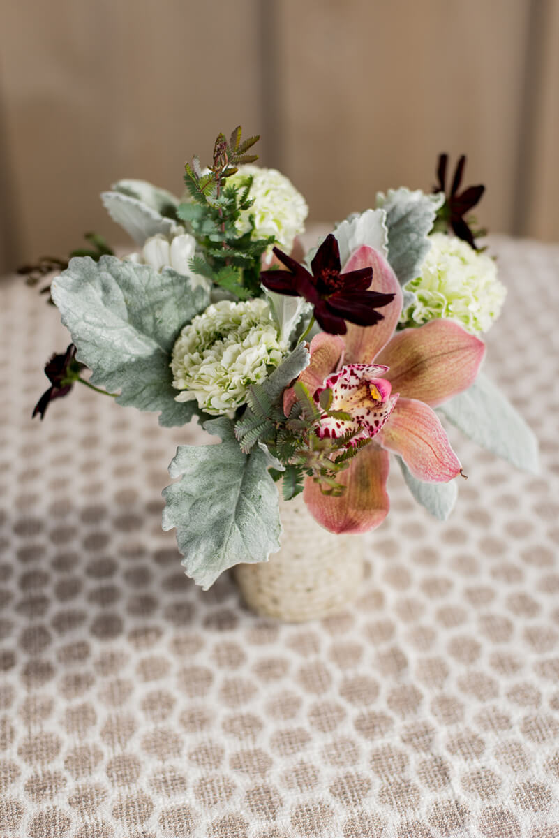 Overhead shot of rustic floral centerpiece on round table with wooden wall backdrop