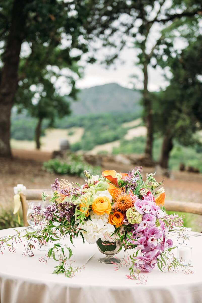 Vibrant wedding floral centerpiece on table with Sonoma county hills in background
