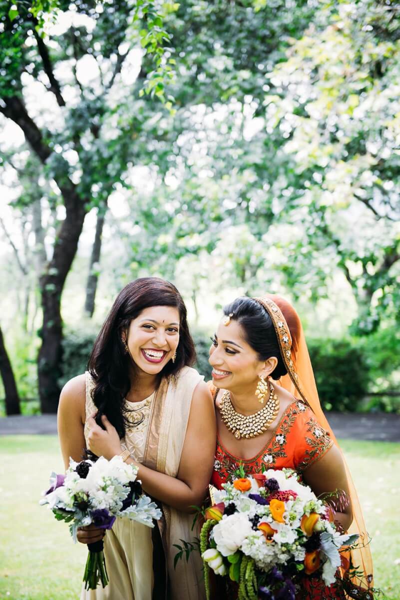 Bride and bridesmaid laughing outdoors while holding bridal and bridesmaid bouqets at Kunde Family Winery wedding