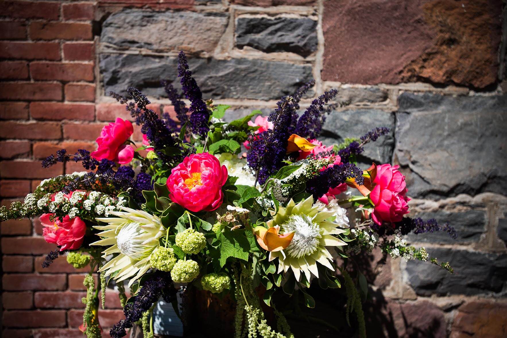 Vibrant wedding floral arrangement set in front of rustic brick background