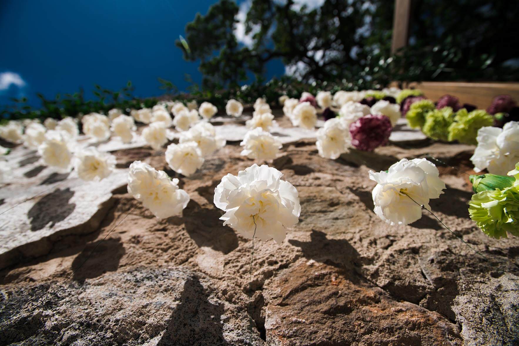White wedding flowers strung up and hung on rock wall at Kunde Ruins in Sonoma