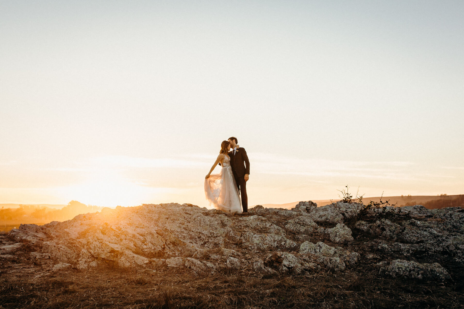 Bride and groom embracing outdoors on hill, under the Marin county sunset