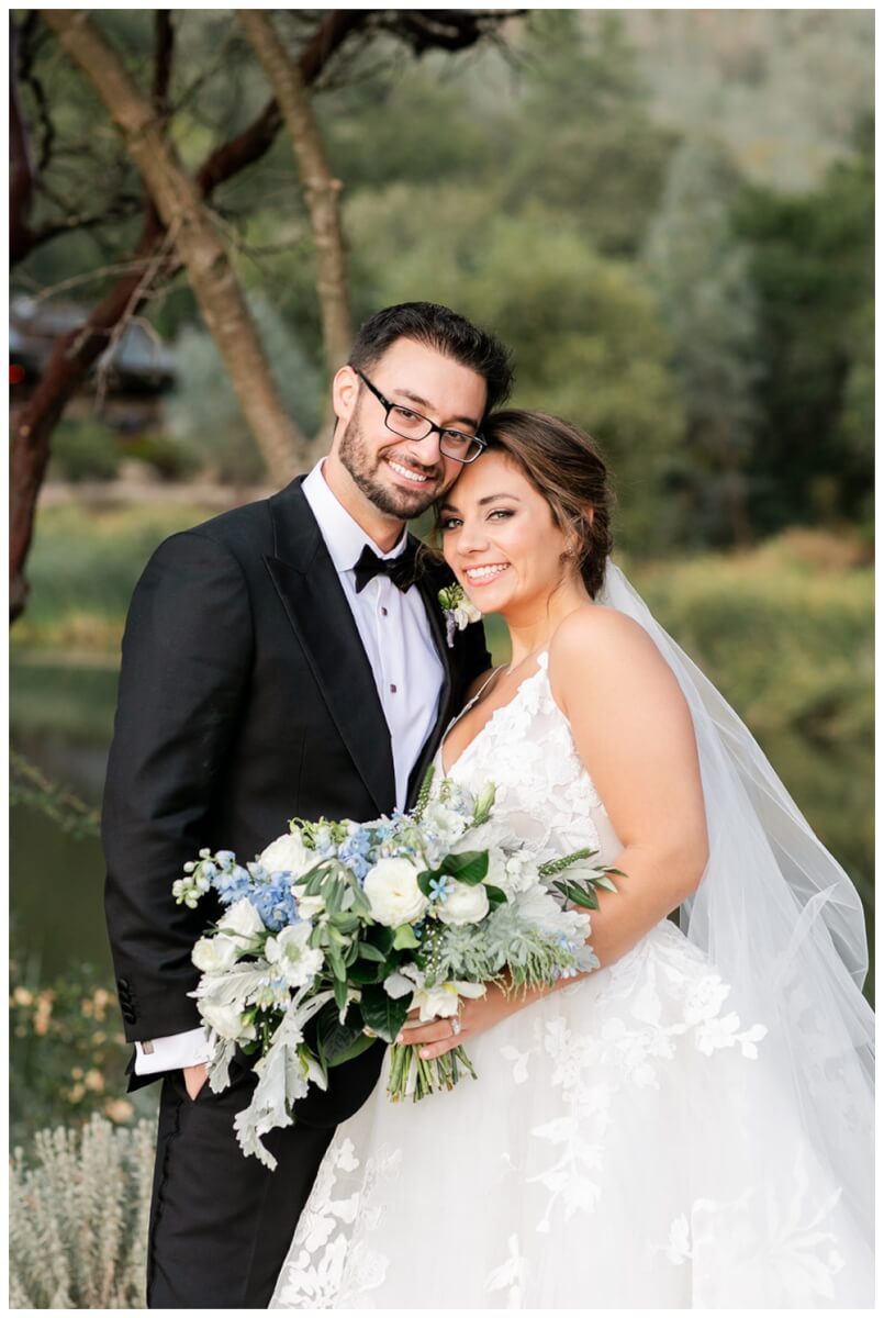 Groom and bride embracing, bride holding organic soft blue and cream bridal bouquet, Aimee Lomeli Designs, Calistoga Ranch Wedding Florist