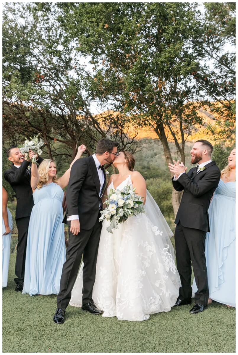 Bride and groom kiss while bridal party cheers at Calistoga Ranch Wedding. Soft Blue & Cream Bridal Party Inspiration, Aimee Lomeli Designs, California Wedding Florist