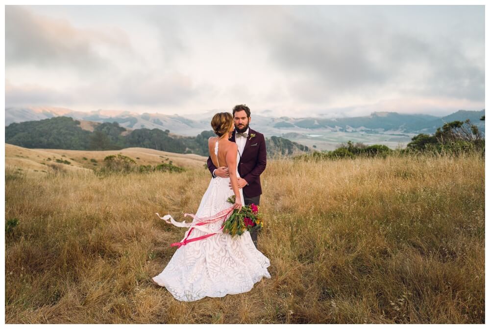 Groom looking at the camera while embracing his bride at a romantic bohemian wedding in the hills of Sonoma County