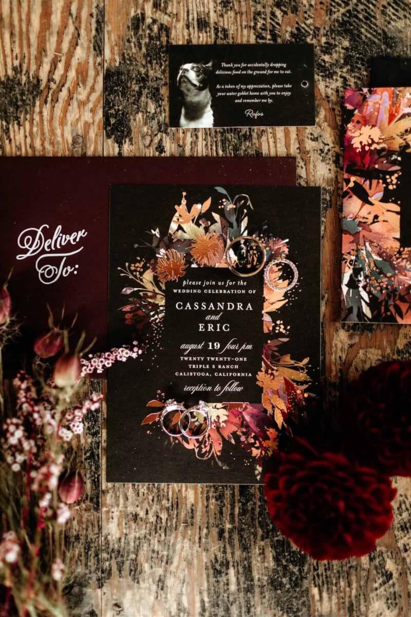 a wedding invitation with floral accents on an elegant wooden table