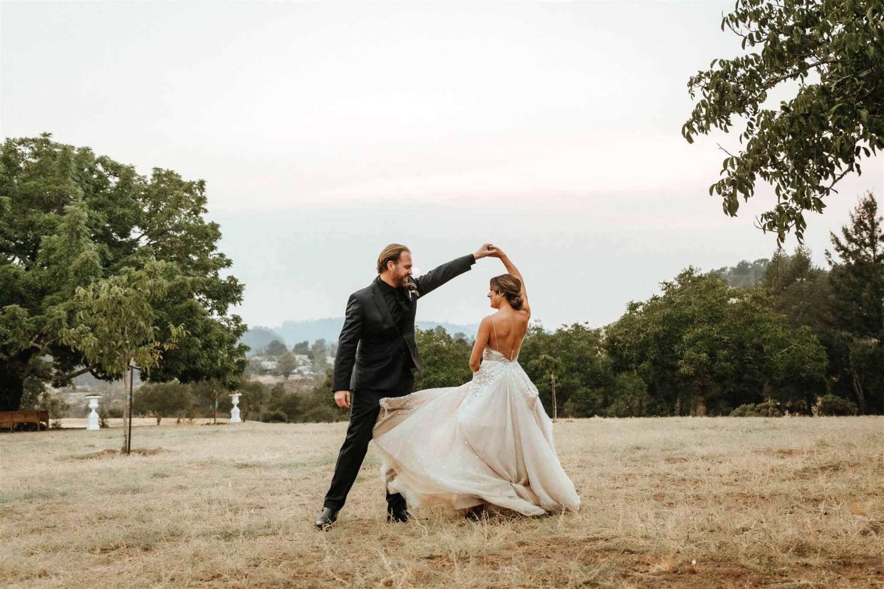 a bride and groom dancing in a field