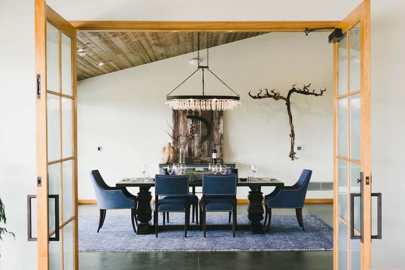 a dining table at a winery with a modern bulb chandelier, branch wall hanging