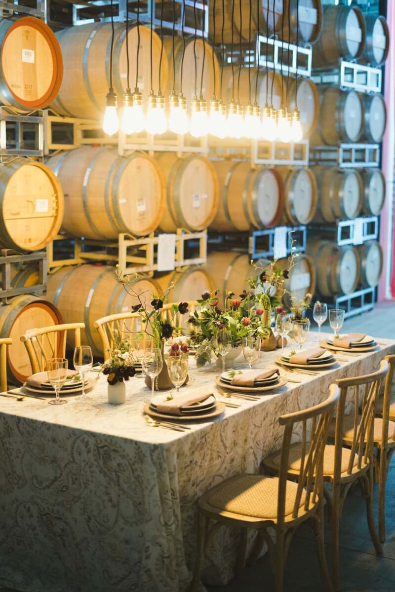 a table is set with elegant flowers and wine barrels behind it