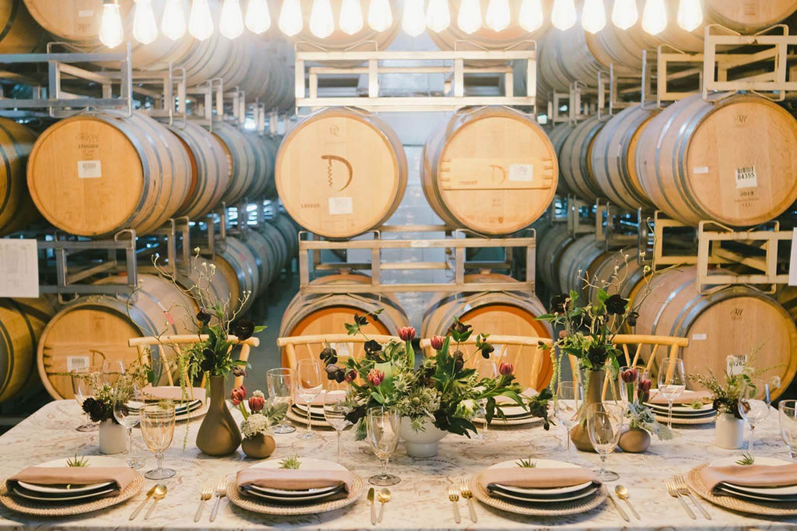table set with beautiful flowers and wine barrels in background