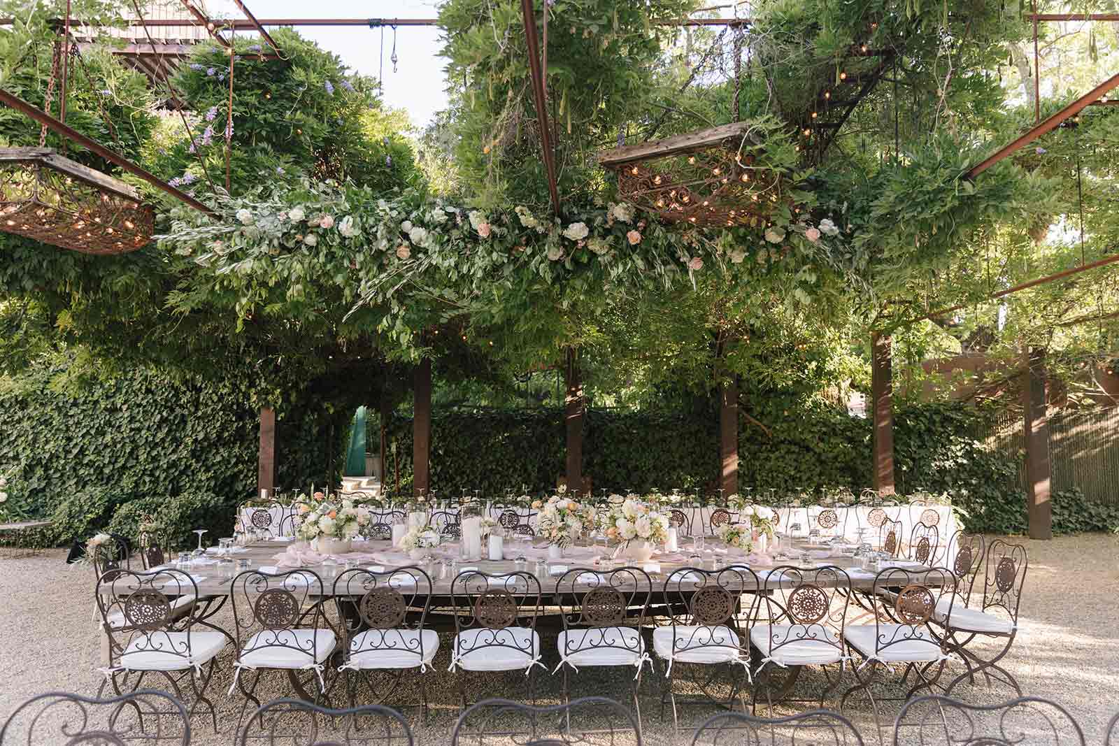 tables set up for the wedding dinner under a canopy with flowers overhead and in vases on the table