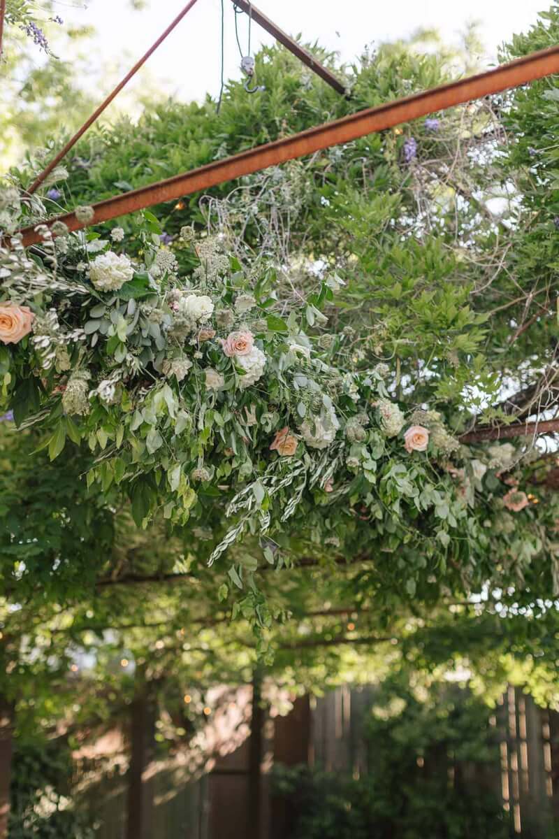 a bunch of wedding flowers and greenery hanging from a trellis