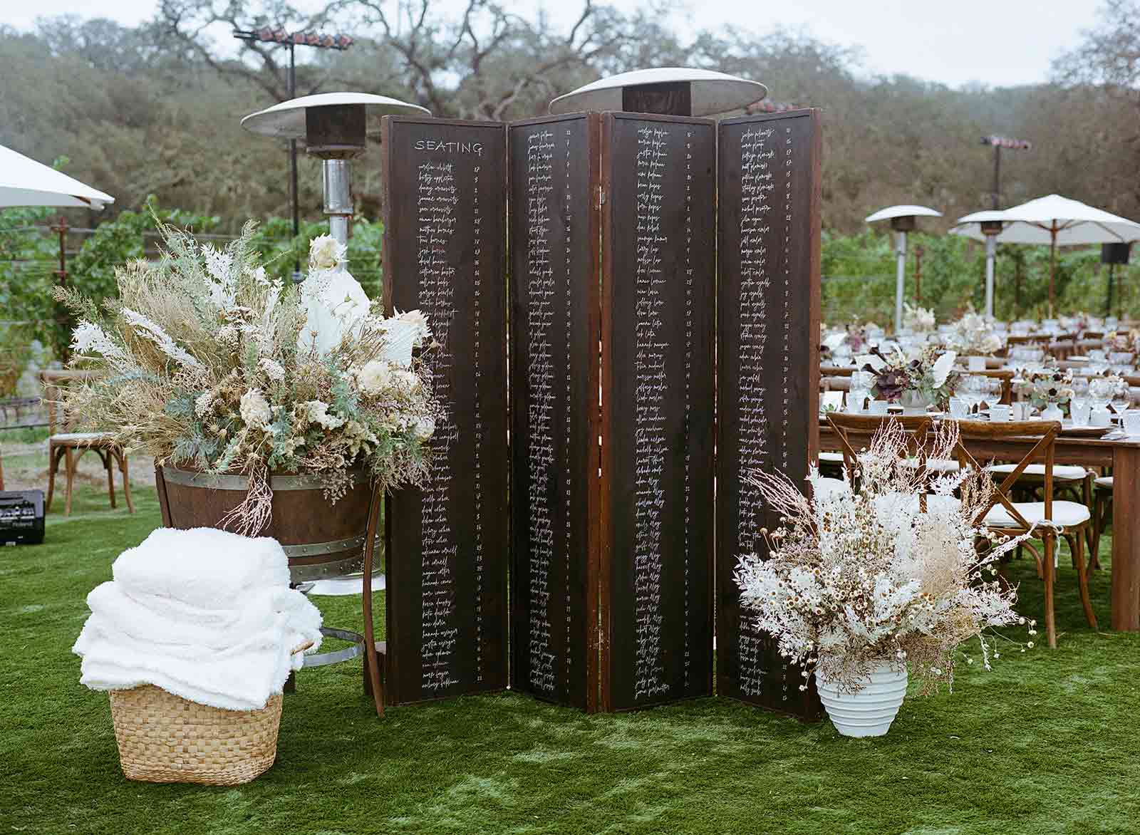 the wedding seating chart on a tall folding screen with large custom dried flower arrangements on either side