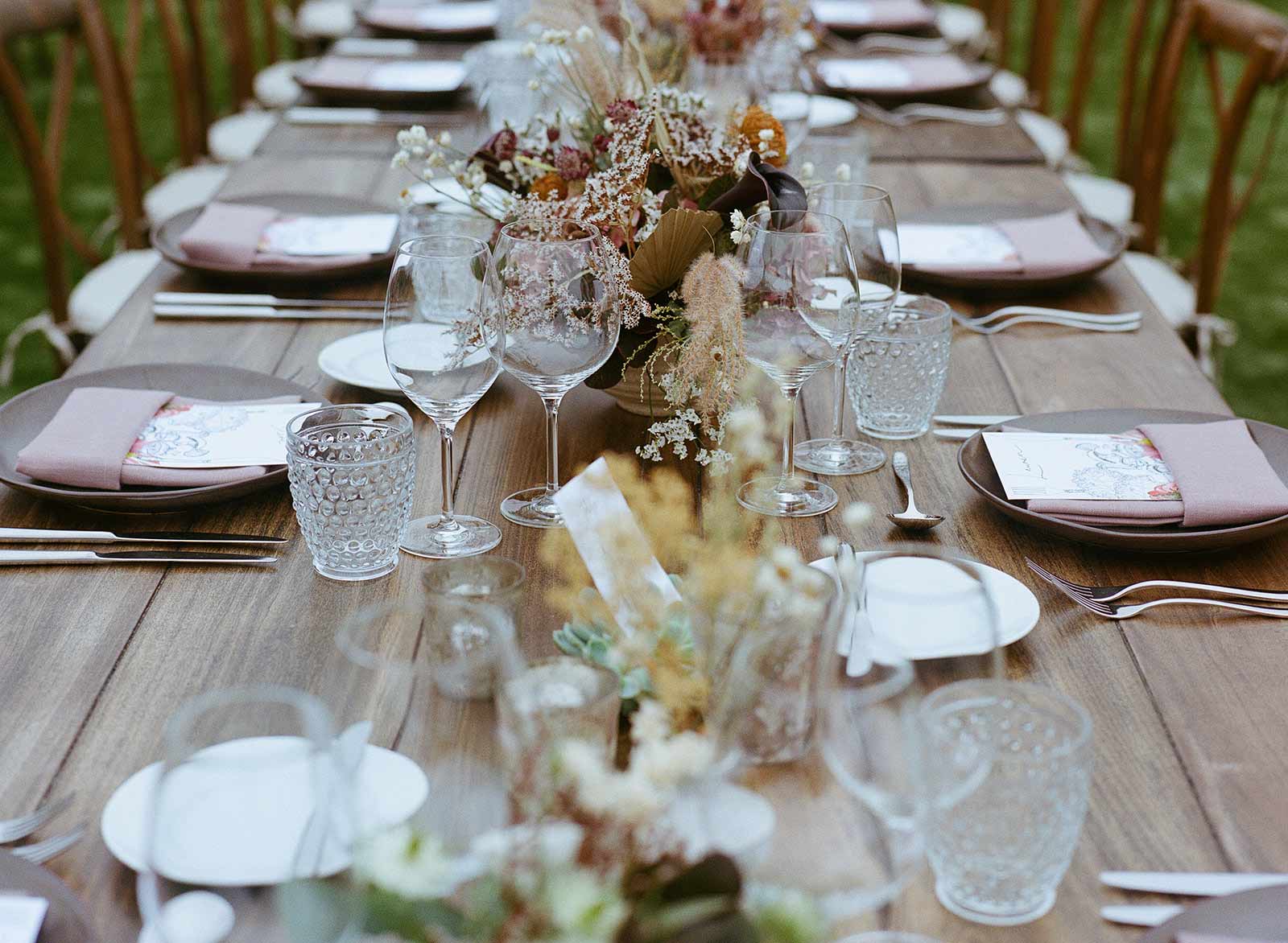 close up of flowers in a moody palette running down the center of a wedding table