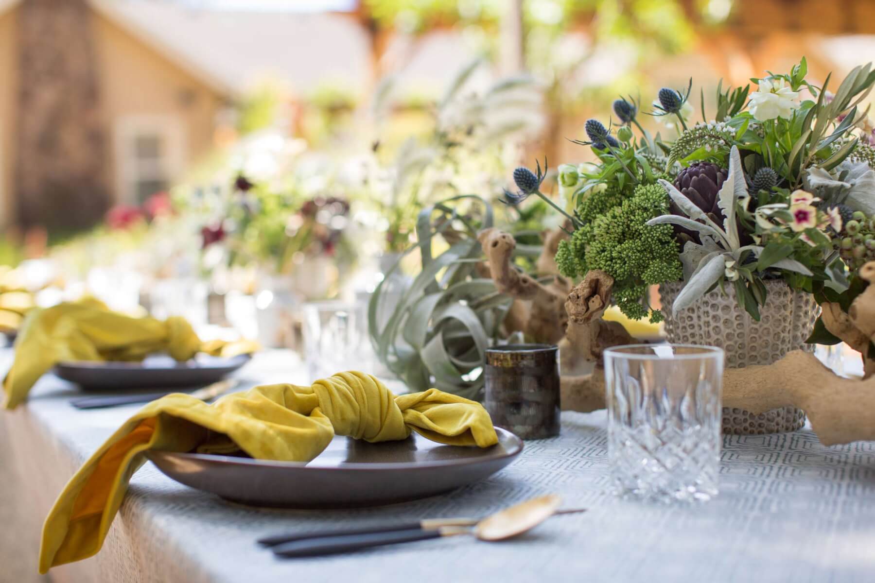 a table set with gorgeous flowers, place settings and crystal for an outdoor garden party