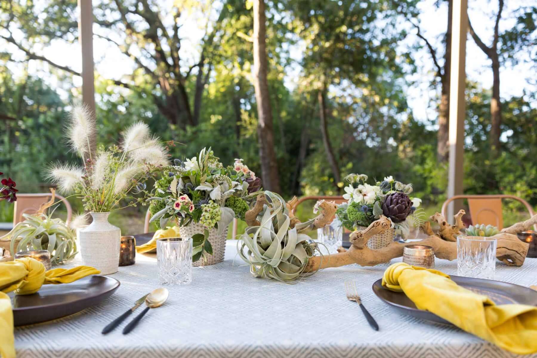 an outdoor table set with abundant flowers and air plants for a wine country private event