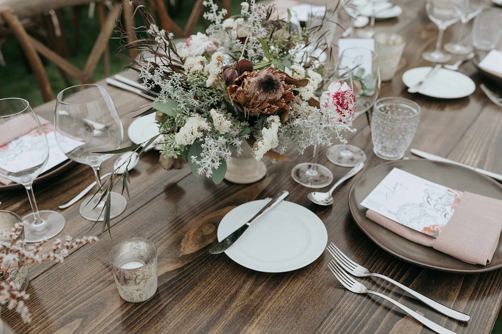 a dried and fresh flower arrangement on a wedding table