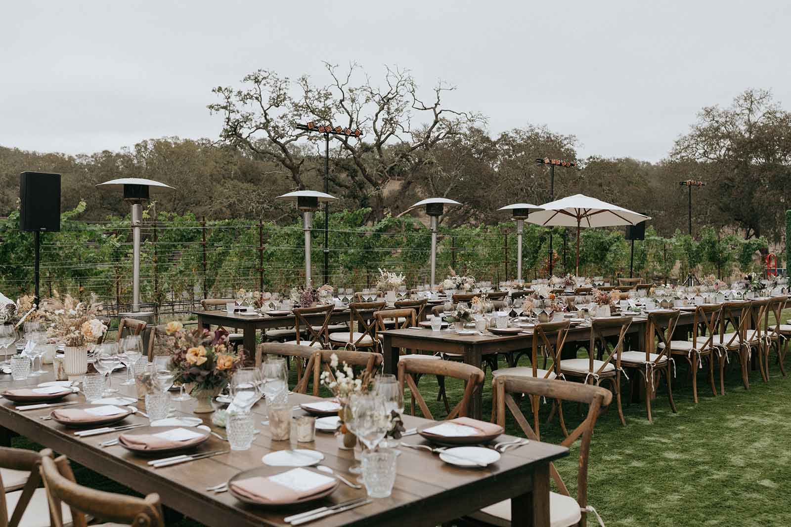 wedding tables set with deep moody florals and vineyards in the background