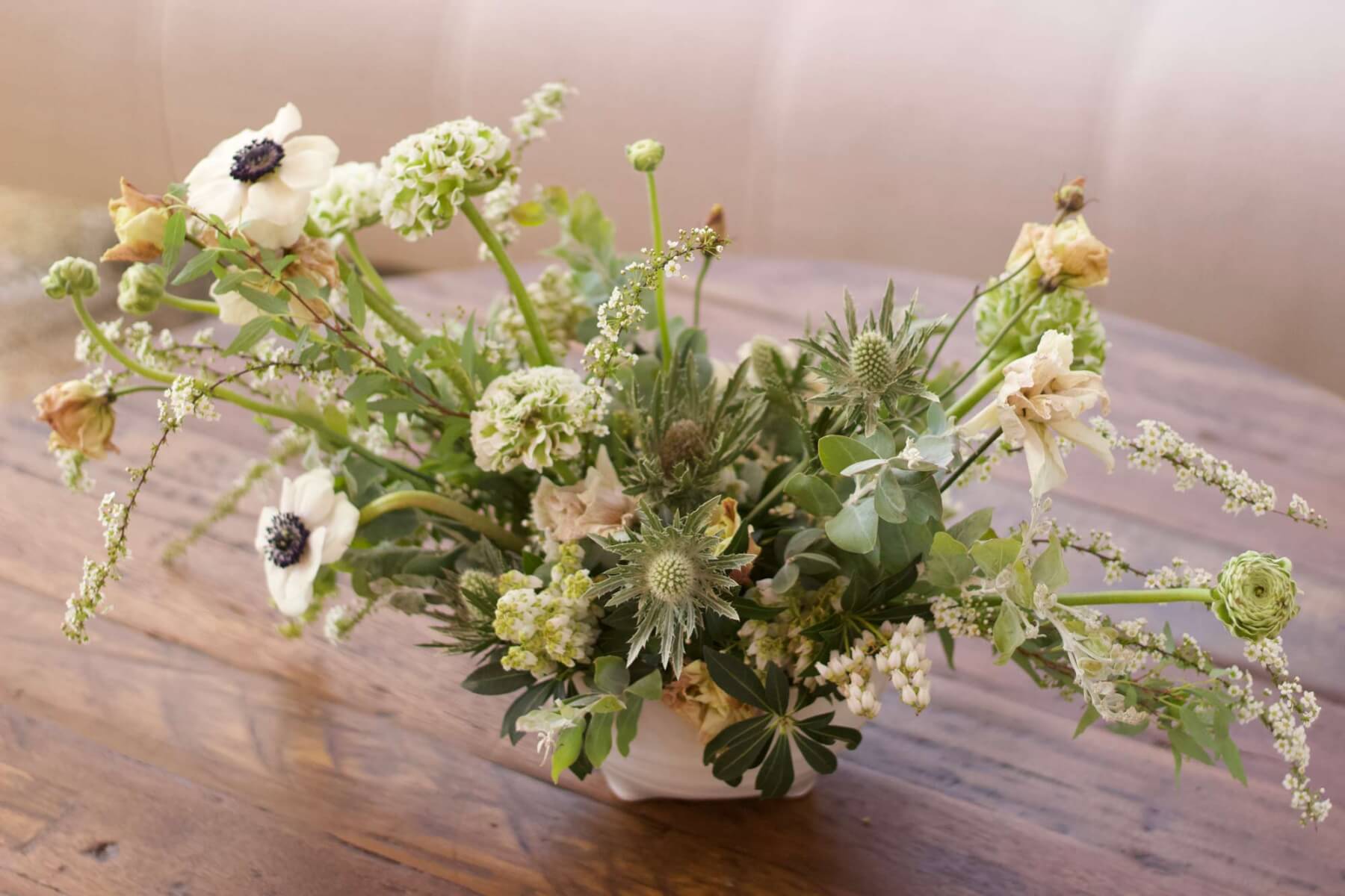a vase filled with white flowers on top of a wooden table at a wine country corporate event