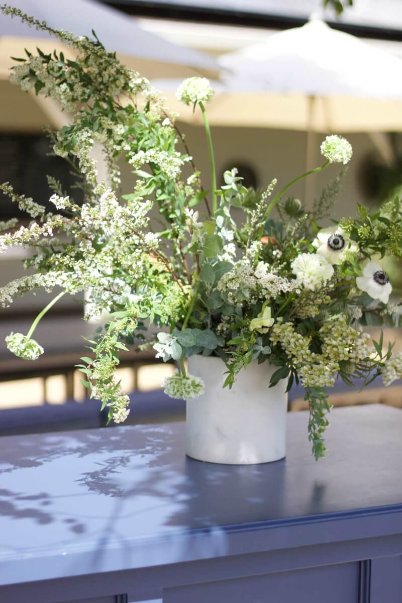 a white vase filled with flowers on top of a blue table at a wine country corporate event