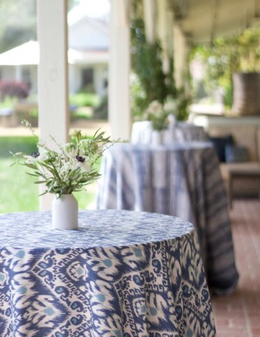 outdoor tall winery tables set with blue and white tablecloths and white vases filled with flowers and greenery