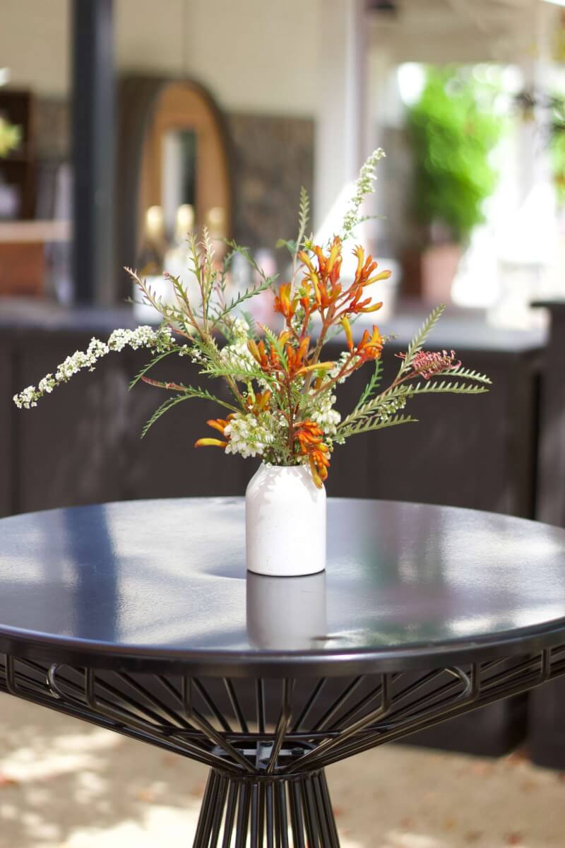 a vase of bright flowers sitting on top of a table at a wine country corporate event