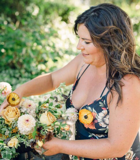 Aimee Lomeli in a floral pattern dress arranging flowers for a wine country event