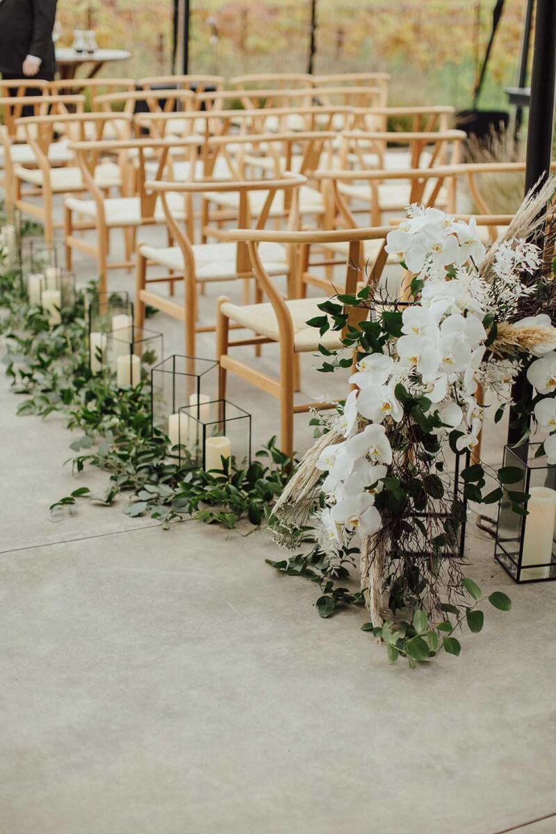 wedding chairs set up with elegant white bouquets and candles with greenery