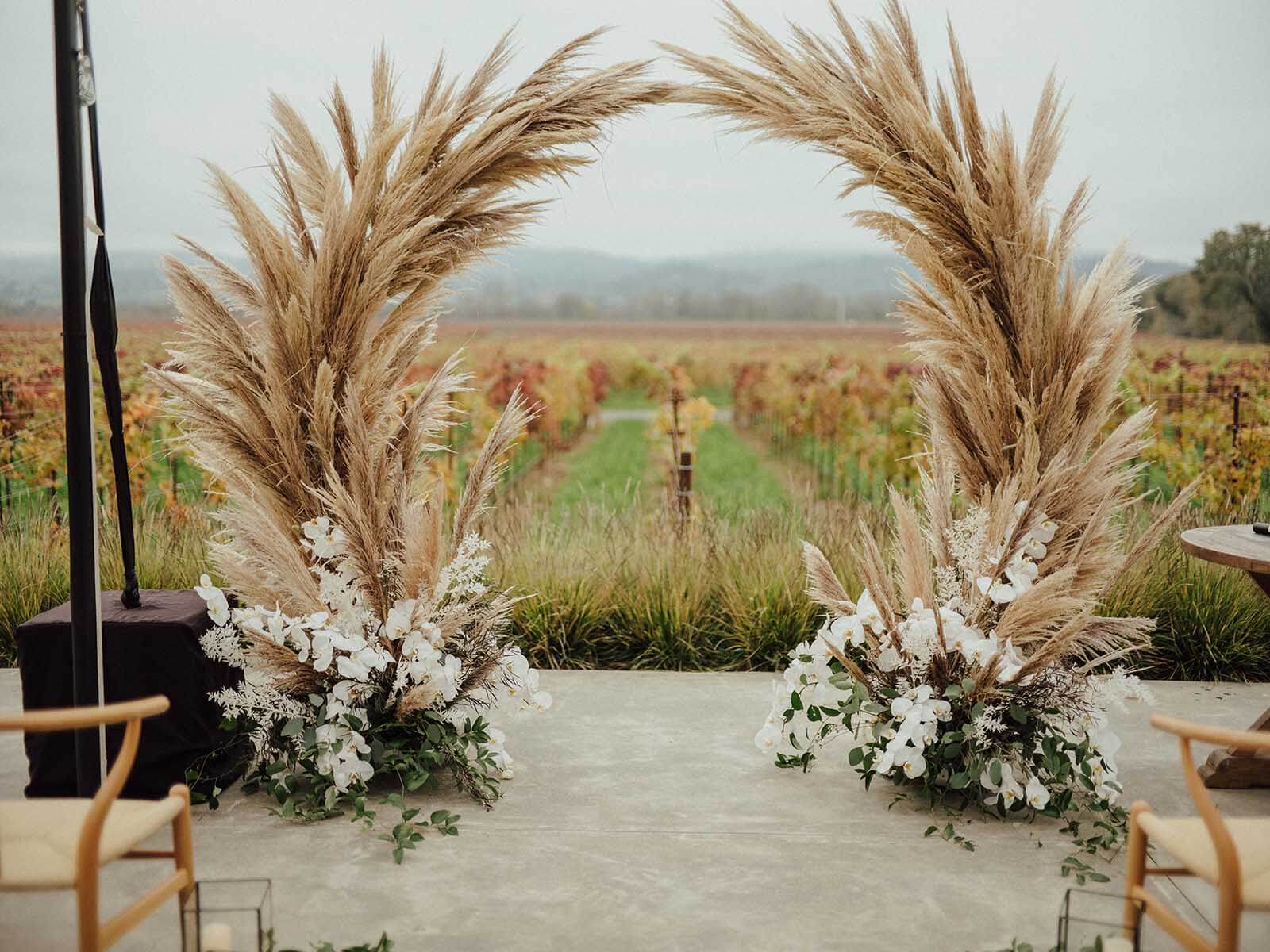 pampas grass arch with white flowers at the base for the wedding ceremony