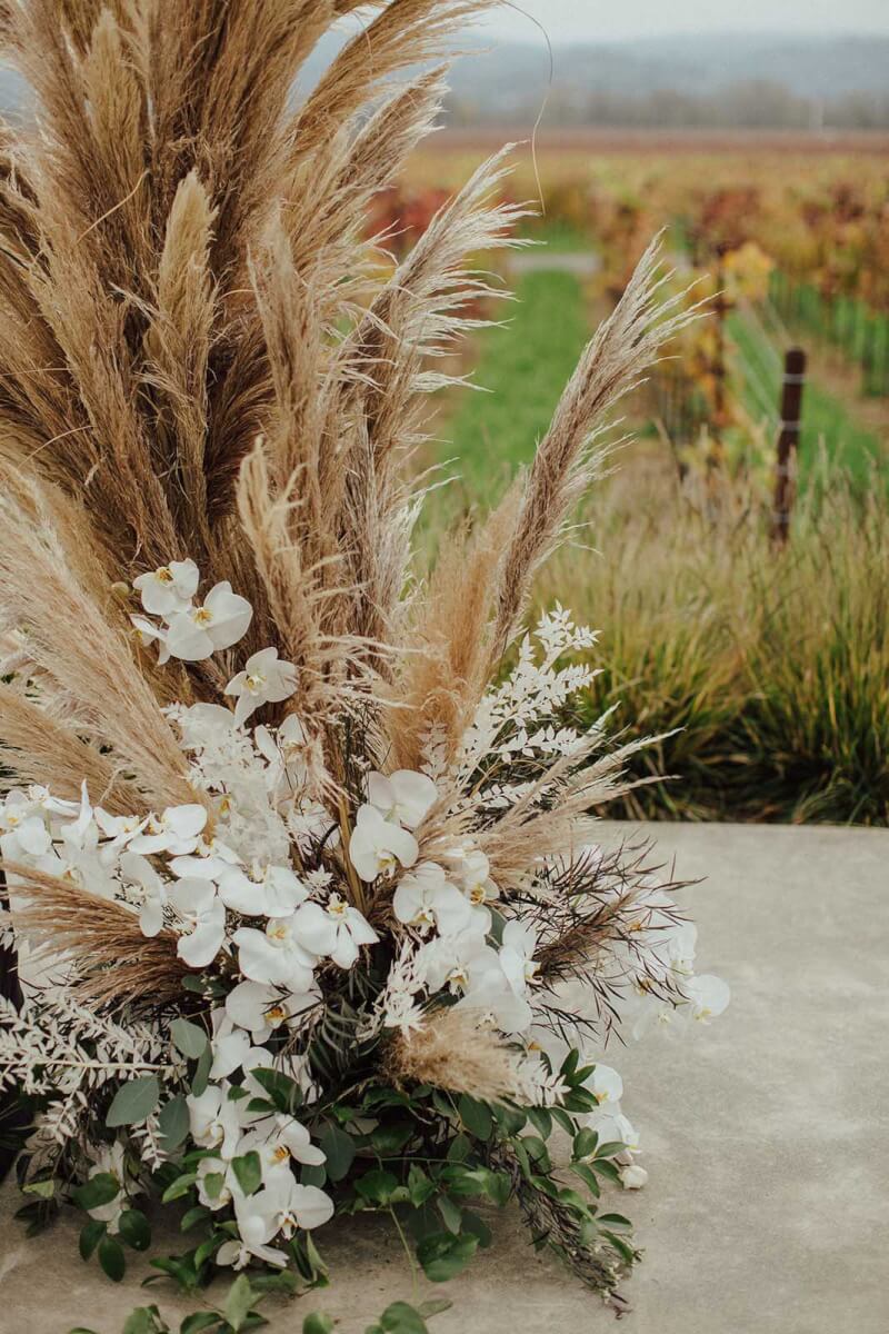 the base of the pampas grass arch with white flowers and greenery