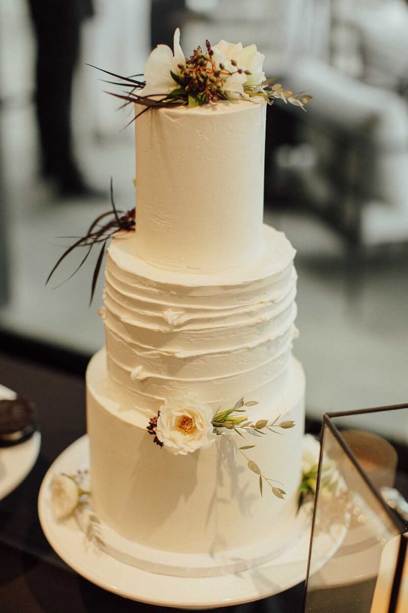 the wedding cake frosted in white and adorned with black and white flowers