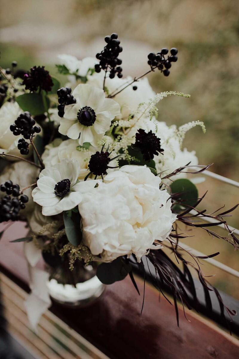A black and white winter wedding bouquet sits on a railing.