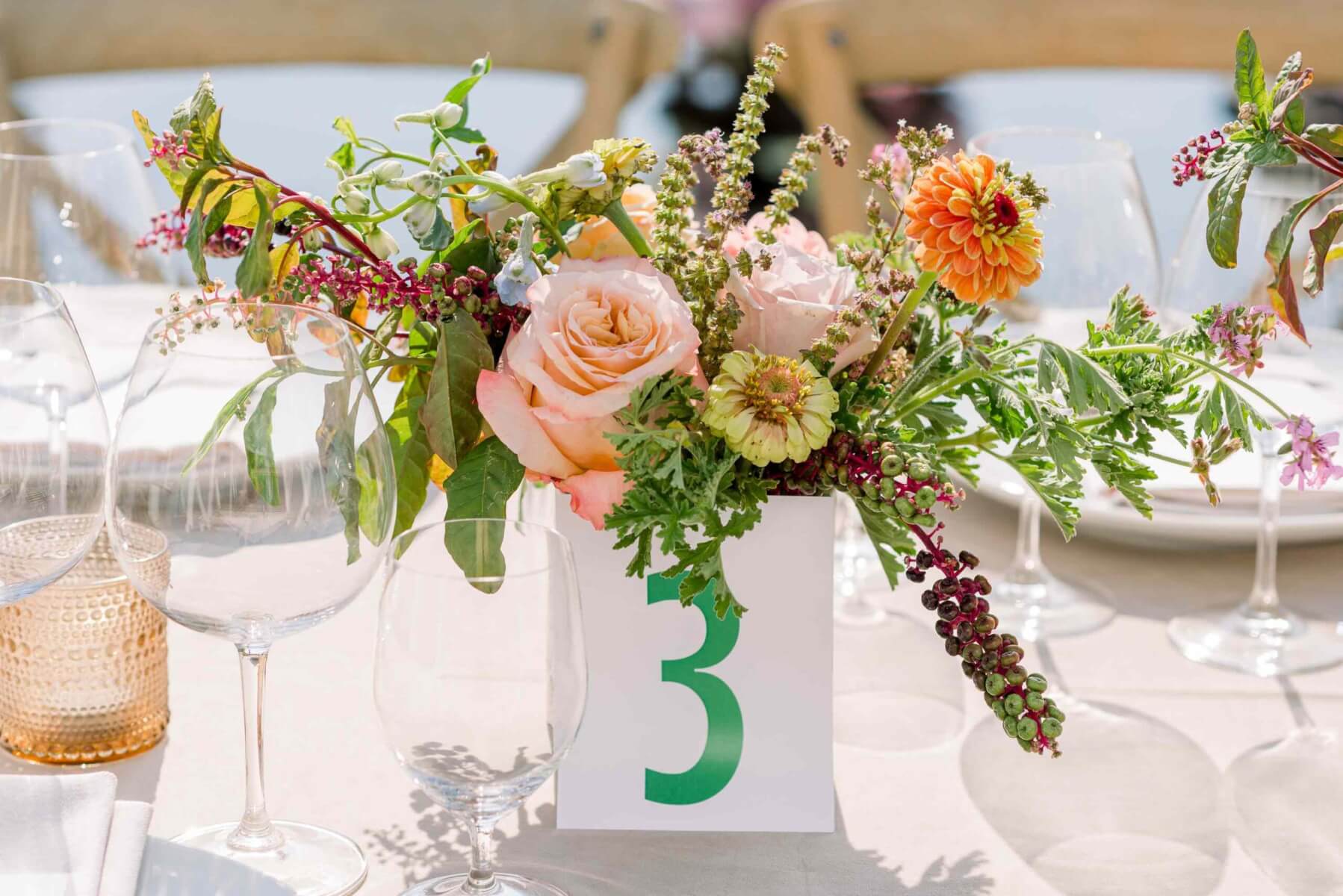 Bright wedding table flowers in playful colors, outdoors on a sunny day.