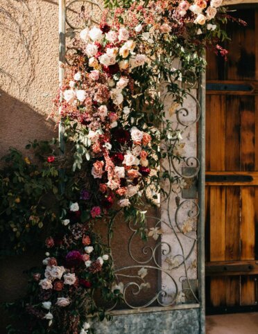 Elegant floral wedding backdrop arrangement on rod iron gates.