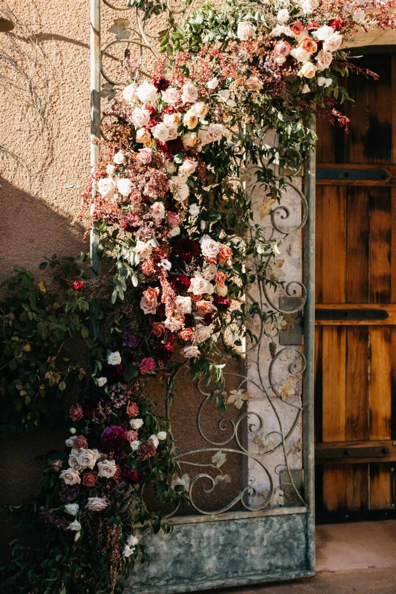 Elegant floral wedding backdrop arrangement on rod iron gates.