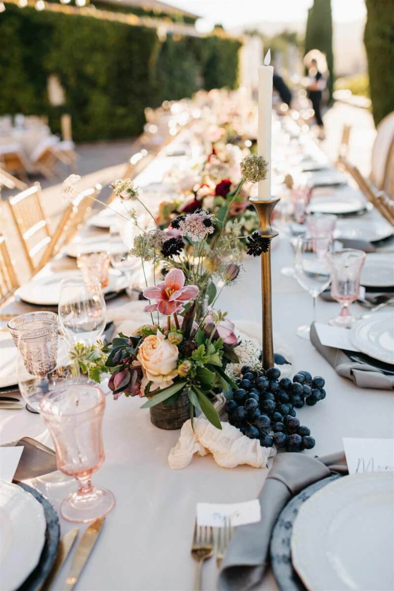 The long wedding table set with elegant floral arrangements and grapes from the local harvest.